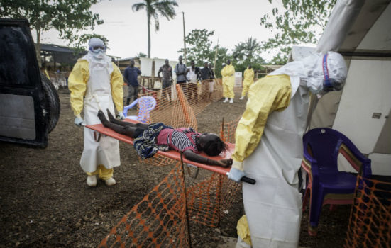 Pigen på båren er blevet syg, og siden hun har været i kontakt med ebola-smittede, bliver hun bragt til vores ebola-center i Kailahun i Sierra Leone. (arkivfoto 9.juli 2014) © Sylvain Cherkaoui/Cosmos.