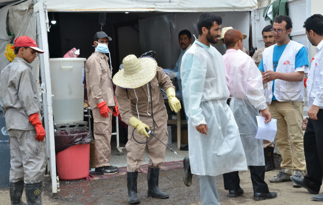 Vagtskifte. En sygeplejerske er lige kommet ud af et af vores kolerabehandlingscentre i Yemen. En medarbejder er i færd med at desinficere hans sko med en klorinholdig væske for at undgå smittespredning.