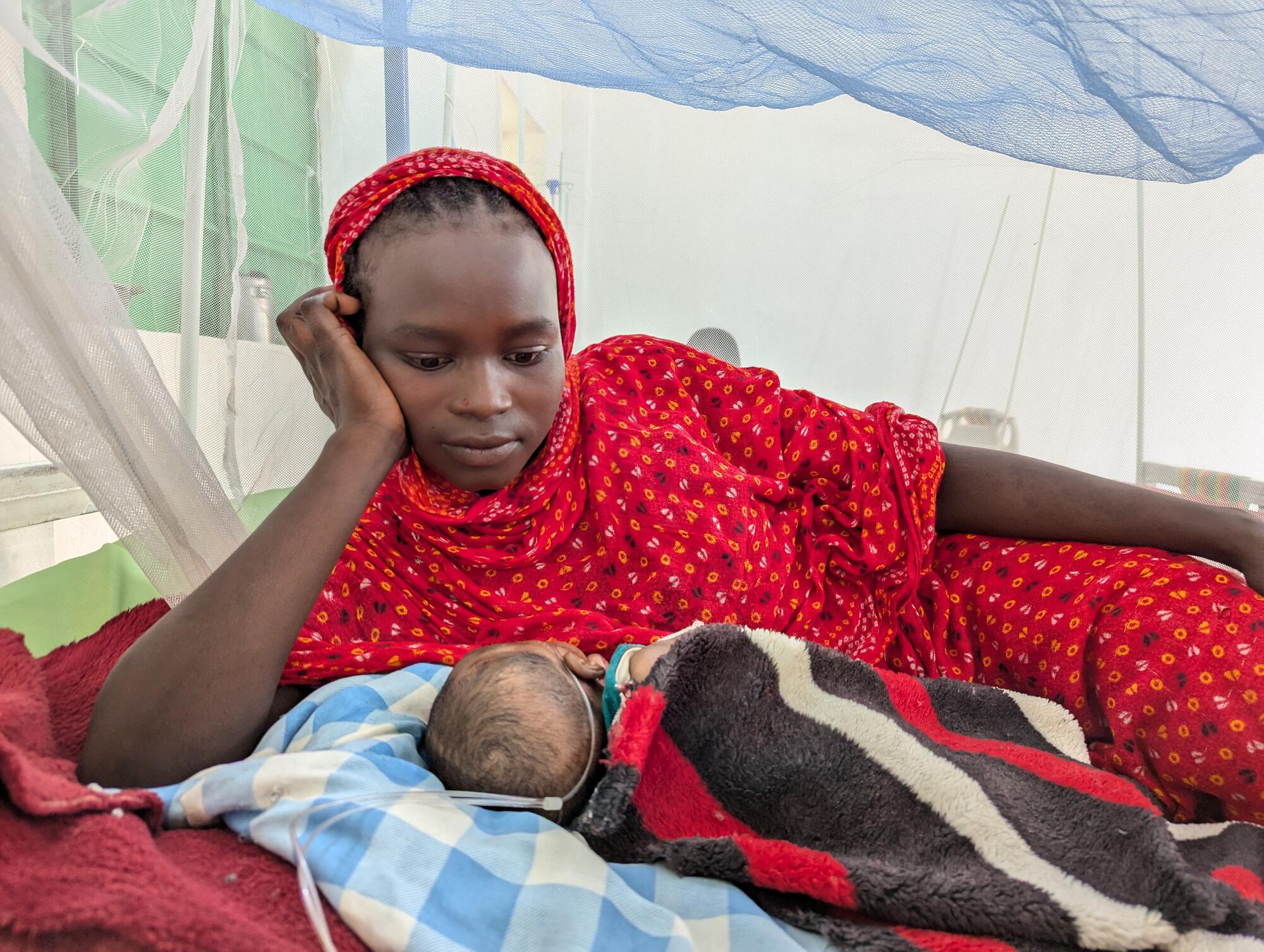 Sudan. Januar 2025. 20-årige Fatna Abdllah er indlagt på intensivafdelingen på Murnei Hospital med sin 1 måned gamle baby, der modtager behandling for hoste. 