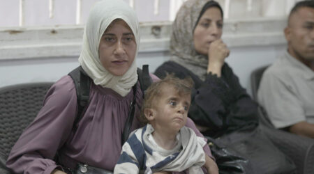 En underernæret kvinde, otte måneder gravid, sidder på en klinik i Gaza by med sin underernærede søn, for at modtage lægehjælp.