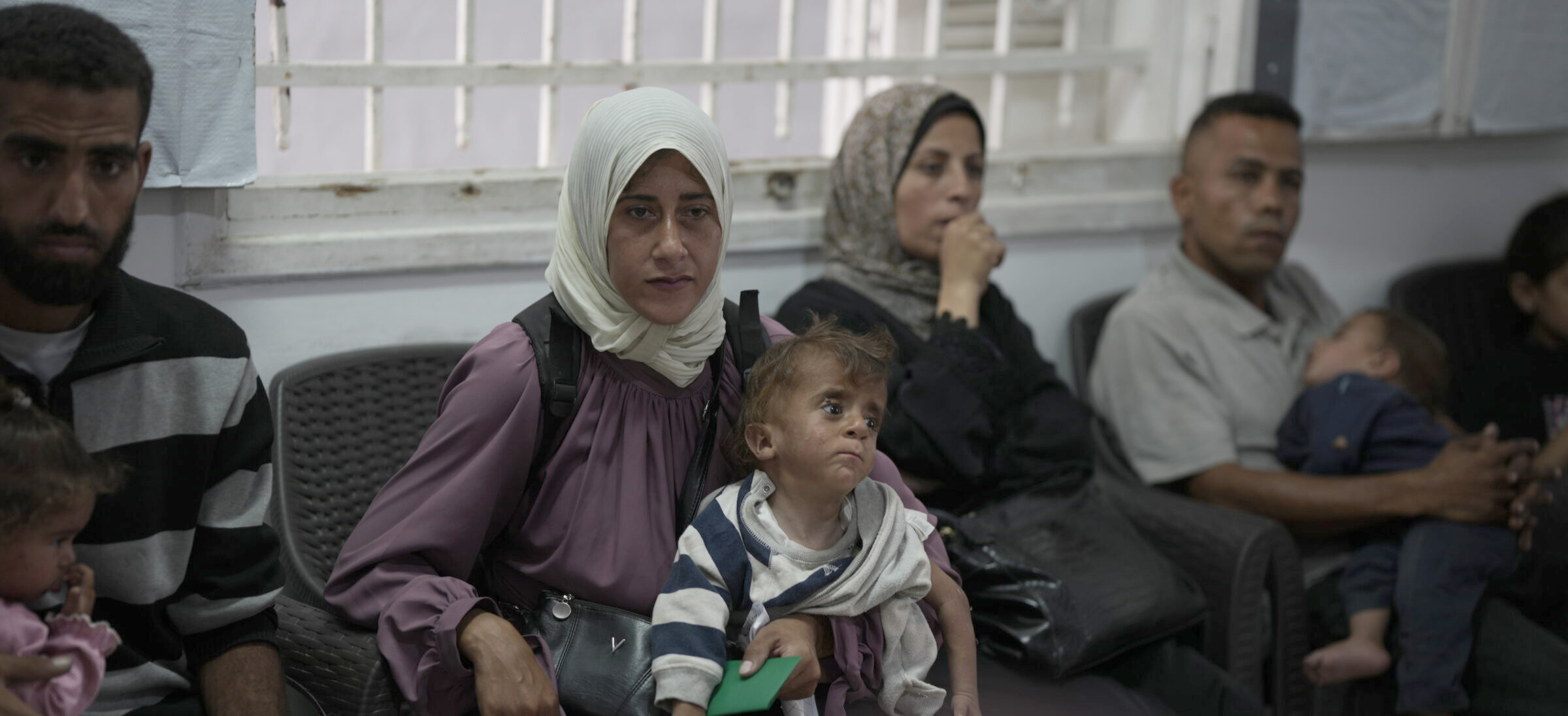 En underernæret kvinde, otte måneder gravid, sidder på en klinik i Gaza by med sin underernærede søn, for at modtage lægehjælp.