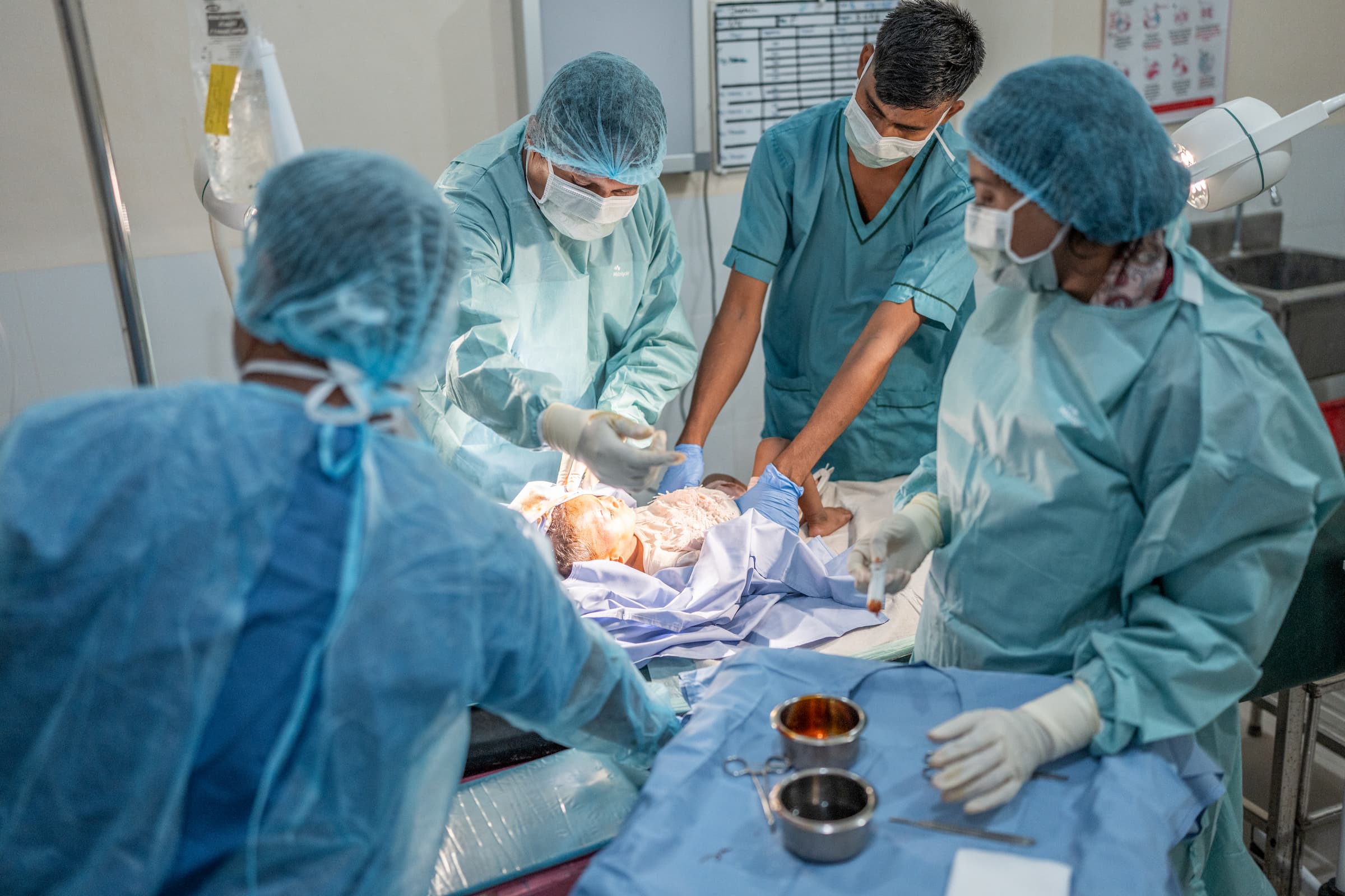 MSF-læge og assistent behandler en absces på hovedet af 16 måneder gammel pige, Josmin, i Kutupalong flygtningelejr, mens hendes mor Salaya støtter hende.