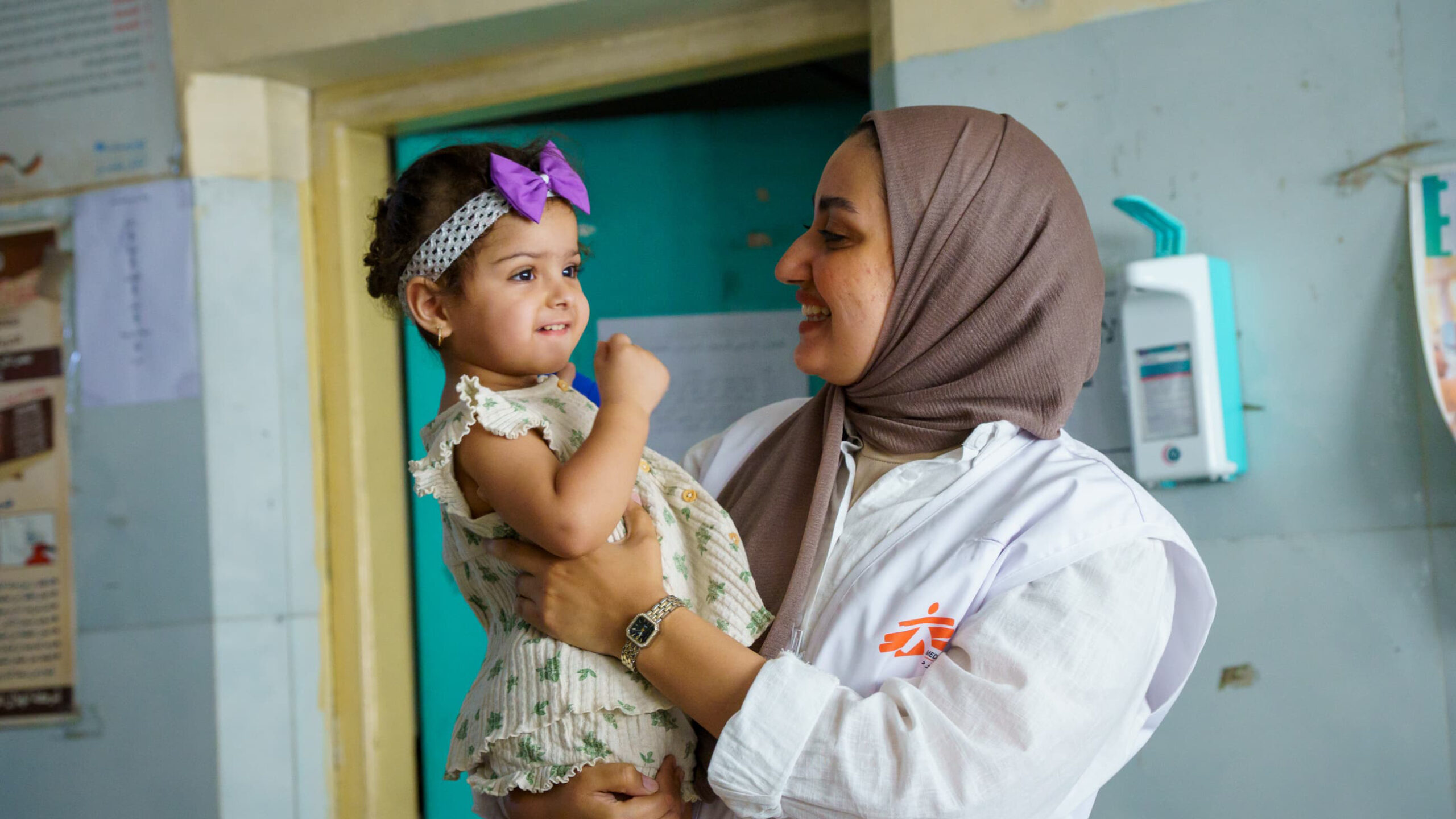 En MSF-sundhedsmedarbejder holder den lille pige Zahraa under et opfølgningsbesøg for TB-behandling på Al-Mahdi Health Center i Sadr City, Bagdad, som led i indsatsen for tidlig screening og oplysning om tuberkulose.