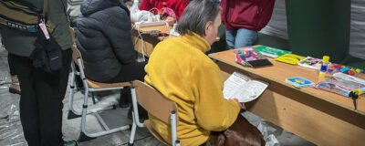 People warm up and wait for their devices to charge inside an emergency tent in Kyiv - Ukraine