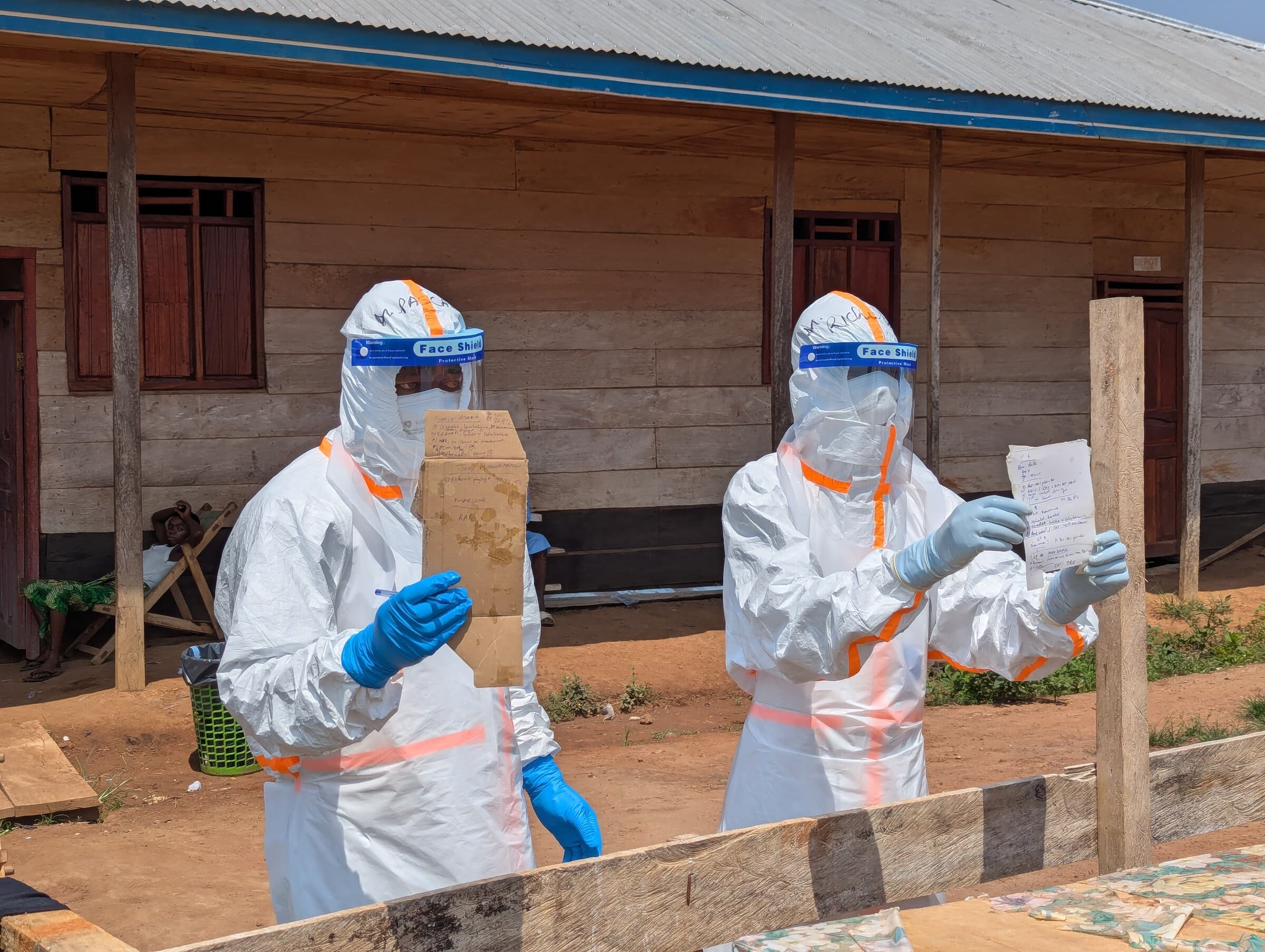 Medarbejdere fra vores medicinske team på ebolabehandlingscenteret i Nia-Nia viser noter frem om de indlagte patienters tilstand. Papirer og andre materialer må ikke tages med ud af hospitalets højrisikoområde, så derfor fotograferer teamet noterne, så de kan gennemgås og deles uden for området.