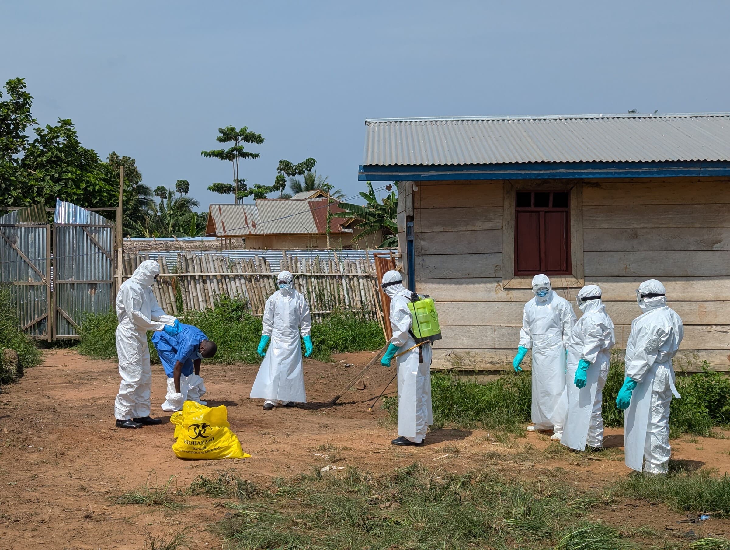 Vores medarbejdere desinficerer deres beskyttelsesdragter udenfor lighuset i Nia-Nia. De har netop håndteret liget af en patient, der døde af mistænkt ebola.